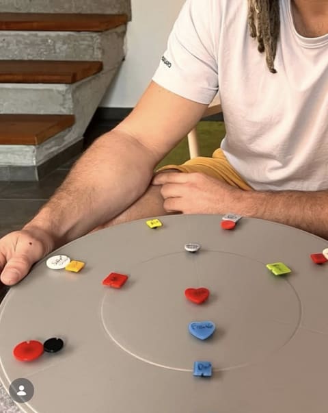 Eine Person legt farbige Figuren auf eine runde Coaching-Scheibe